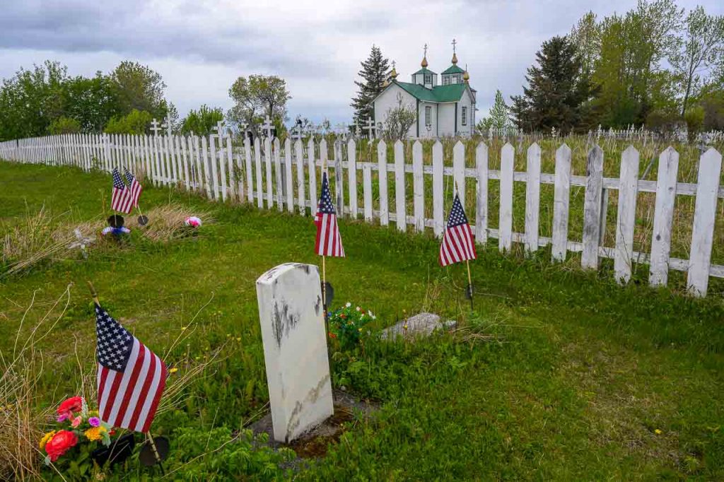Russisch-orthodoxe Kirche und Friedhof in Ninilchik, Alaska, Kenai Peninsula. Im Vordergrund, abgegrenzt durch einen Holzzaun, Grabstätten US-amerikanischer Veteranen.