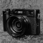 Vorderansicht der Fujifilm X100F in schwarzer Ausführung mit angesetzter Gegenlichtblende