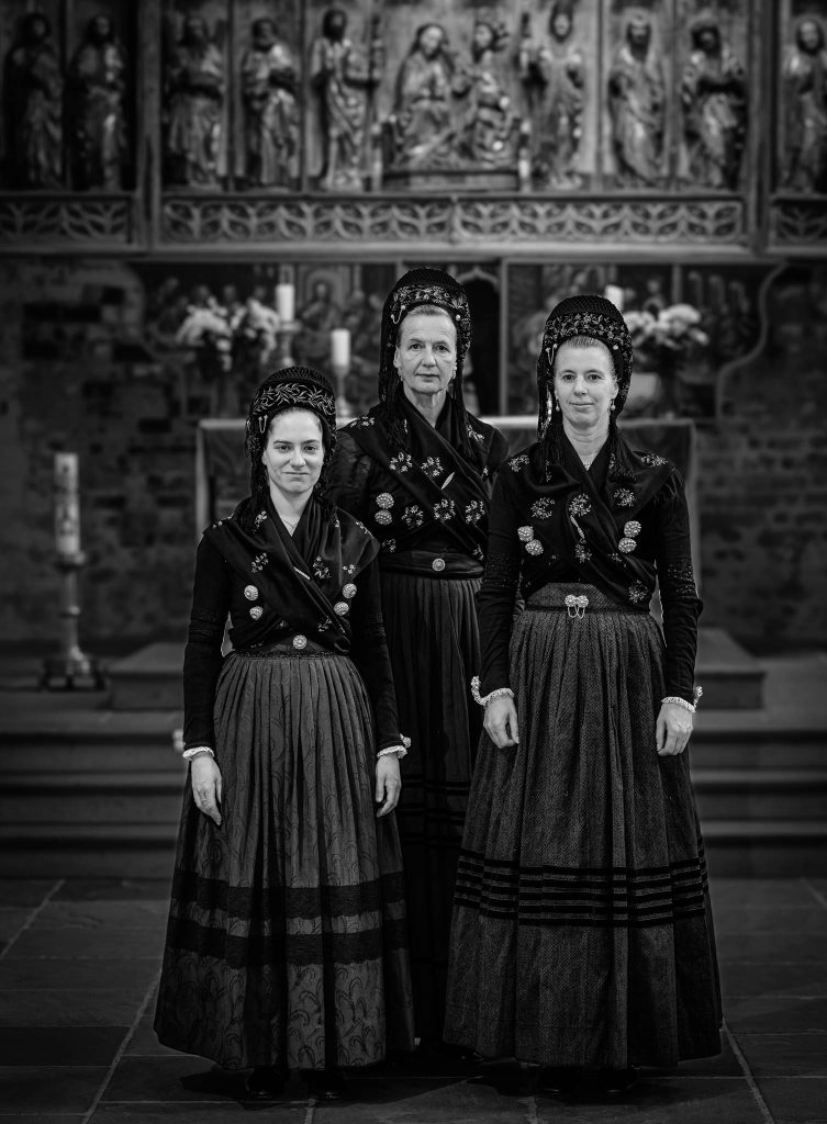 Mareike Böhmer, Helga Wögens und Kerstin Christiansen (v. l. n. r.) von der Utersumer Trachtengruppe vor dem Altar des Friesendoms (St. Johannis) in Nieblum in authentischer Kirchgangstracht.
