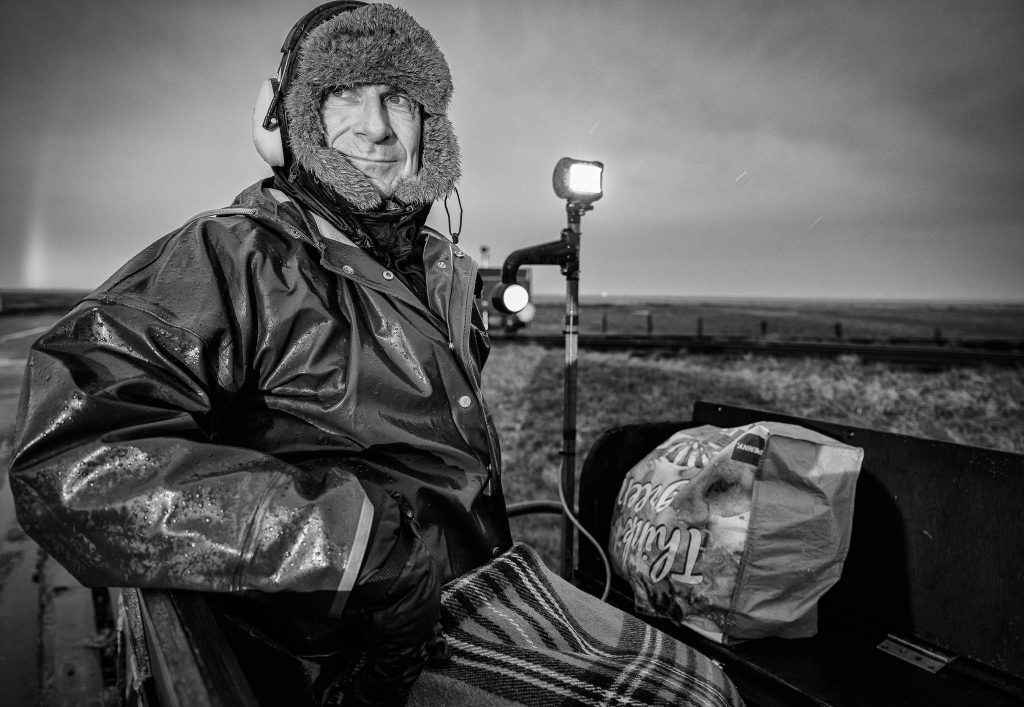 Seit 1994 betreut Pastor Matthias Krämer die Kirchengemeinden auf Langeneß, Oland und Gröde. Seine Lore macht die seelsorgerische Mobilität im Watt möglich – solange Wind und Wasser es zulassen. Bei Landunter oder Sturmfluten bleibt das Pastorat auf Langeneß eine Insel im doppelten Sinn: Dann ist ein Verlassen der Warft nicht möglich.