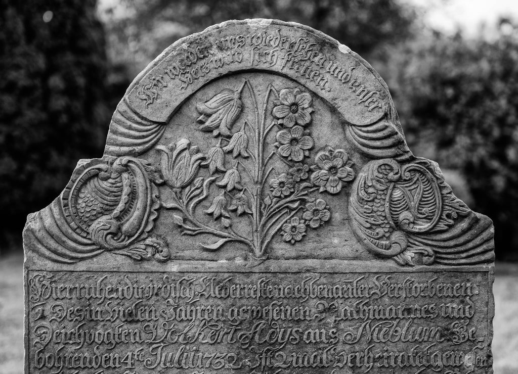 Historischer Grabstein auf dem Nieblumer Friedhof von St. Johannis auf Föhr. Als Teil der berühmten "sprechenden Steine" erzählen diese Denkmäler in eingemeißelter Schrift ganze Lebens- und Seefahrtsgeschichten der Inselfriesen.