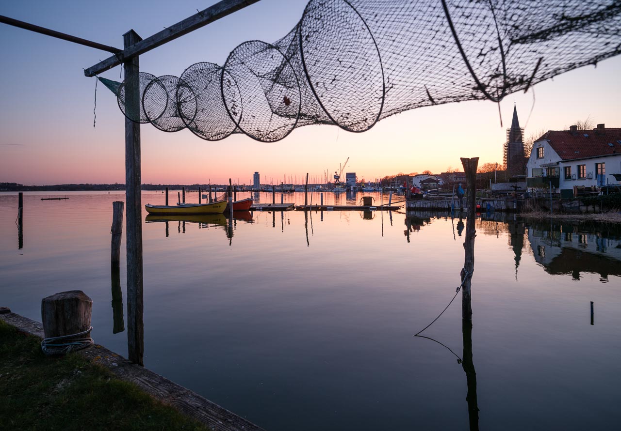 Letztes Abendlicht setzt Boote, Brücken und die Netze der Fischer auf dem Holm in Schleswig an der Schlei in Szene.